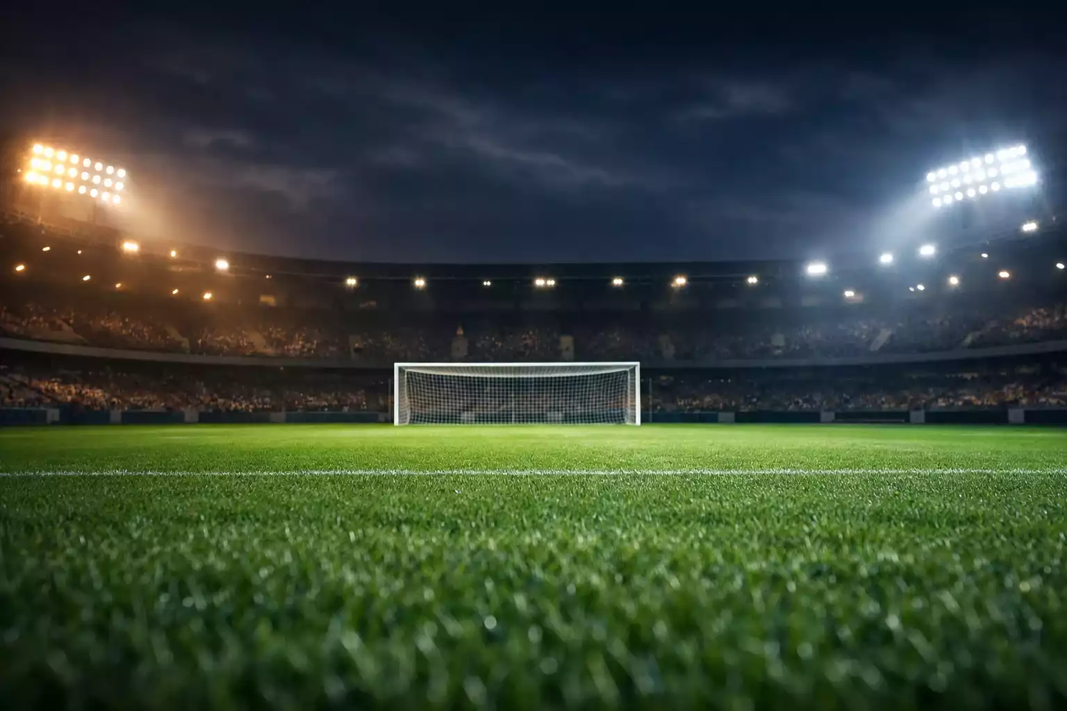 Fußballstadion bei Flutlicht mit Rasen und Tribünen im Hintergrund